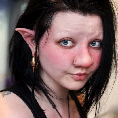 Woman with black hair wearing a troll nose prosthetic