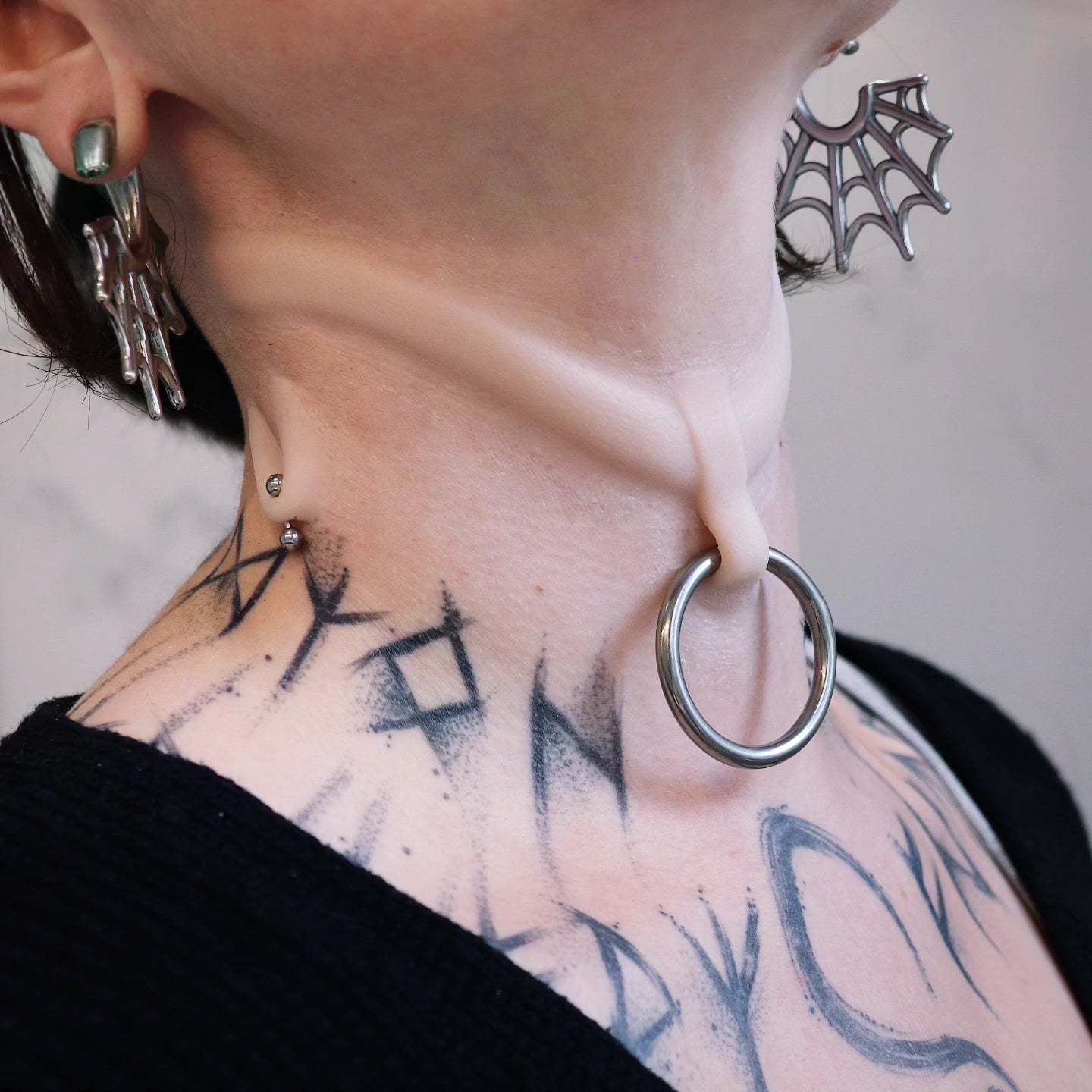 Woman's neck with stretched piercing and subdermal choker prosthetic