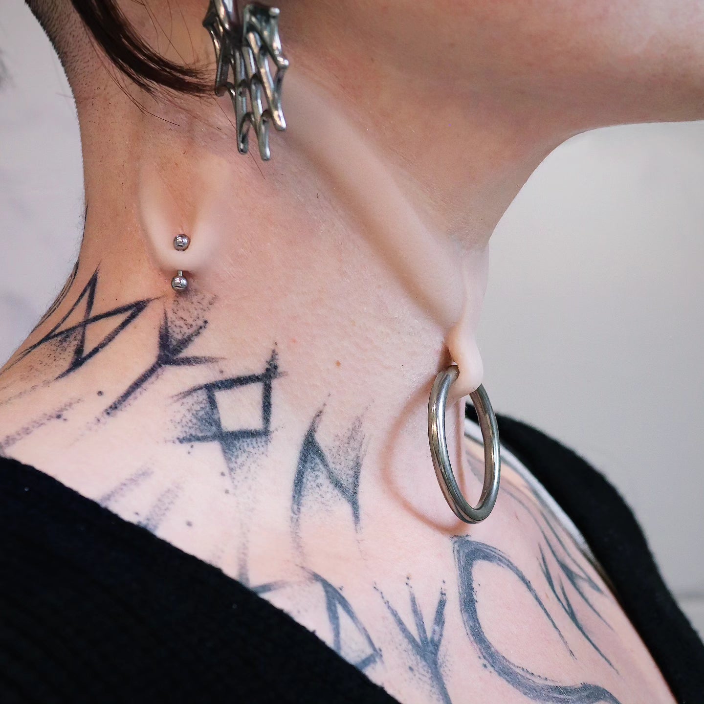 Woman's neck with a stretched piercing and subdermal choker prosthetic
