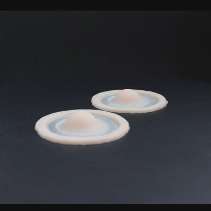 Single subdermal horns prosthetics in vanilla shade on a black turntable, slowly rotating. 