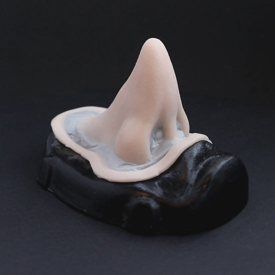 Short pointy nose prosthetic in vanilla shade on a black turntable, slowly rotating. 
