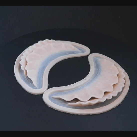 A pair of ruffle gills prosthetics in vanilla shade on a black turntable, slowly rotating. 