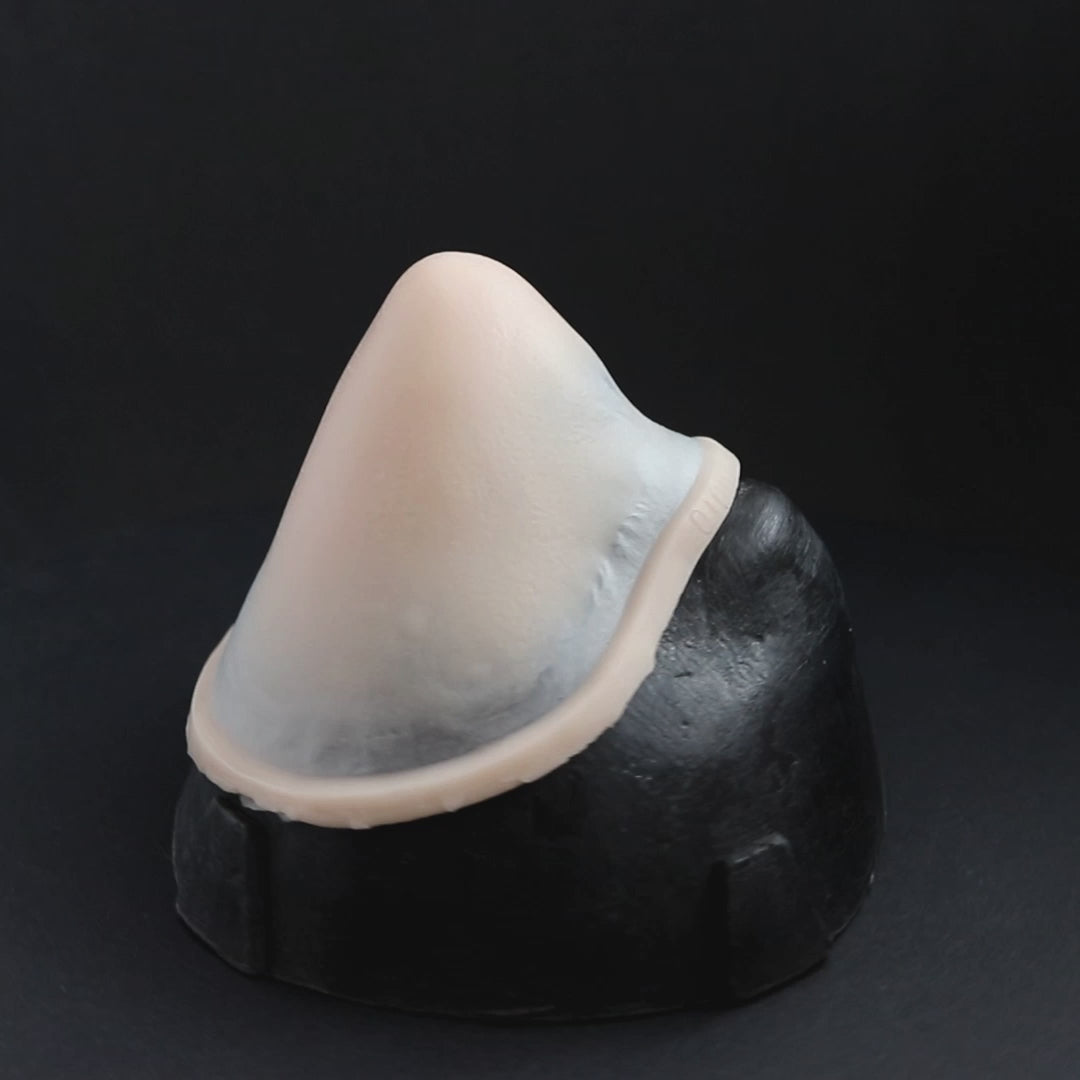 Pointy nose prosthetic in vanilla shade on a black turntable, slowly rotating. 