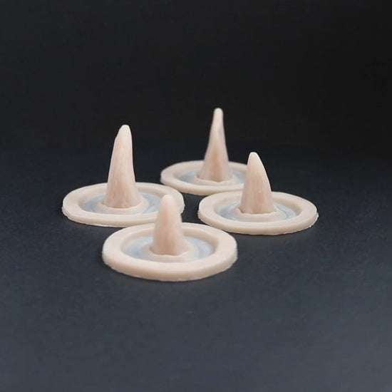 Four small crooked horns prosthetics in vanilla shade on a black turntable, slowly rotating. 