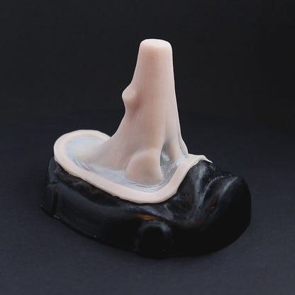 Wooden nose prosthetic in vanilla shade on a black turntable, slowly rotating. 