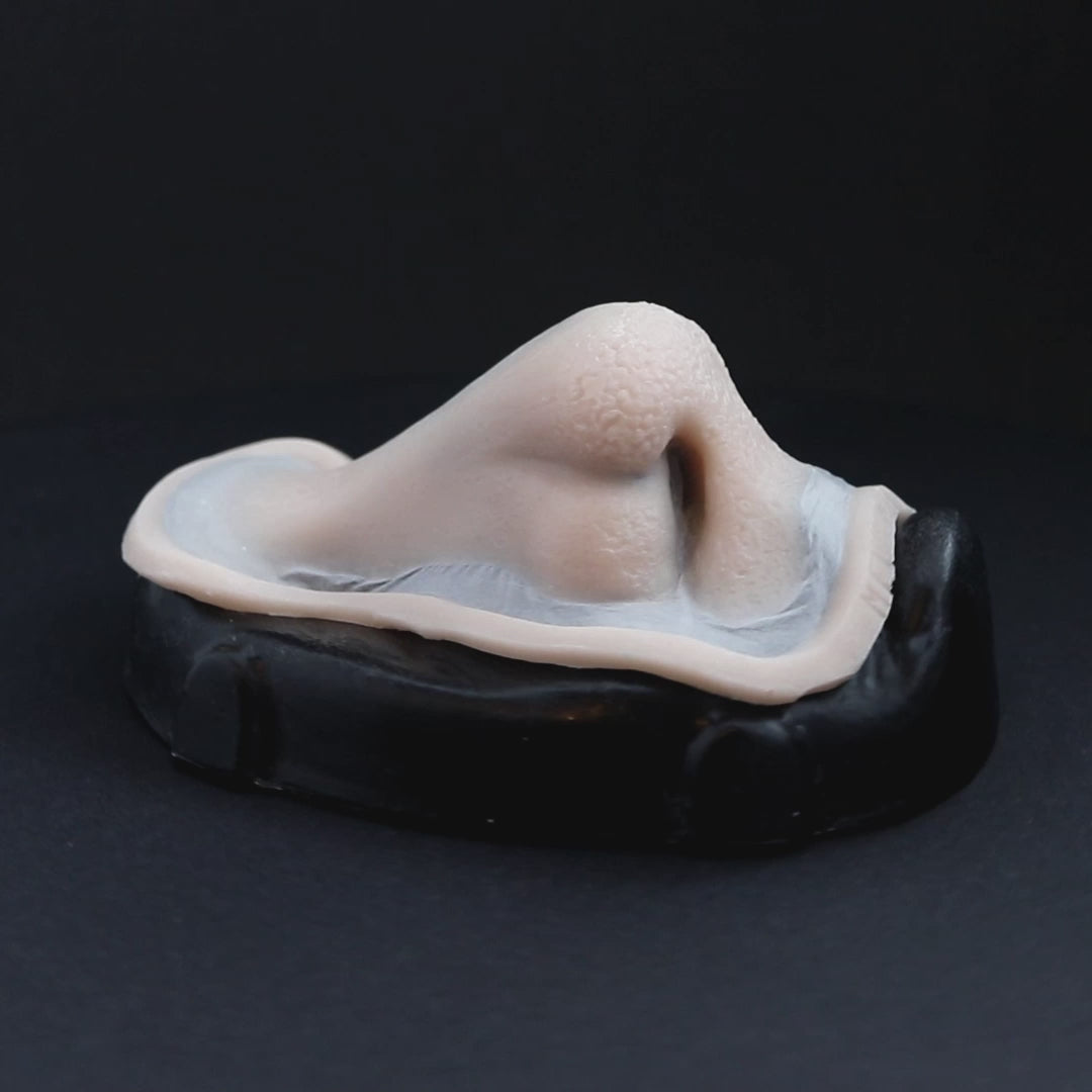 Satyr nose prosthetic in vanilla shade on a black turntable, slowly rotating. 