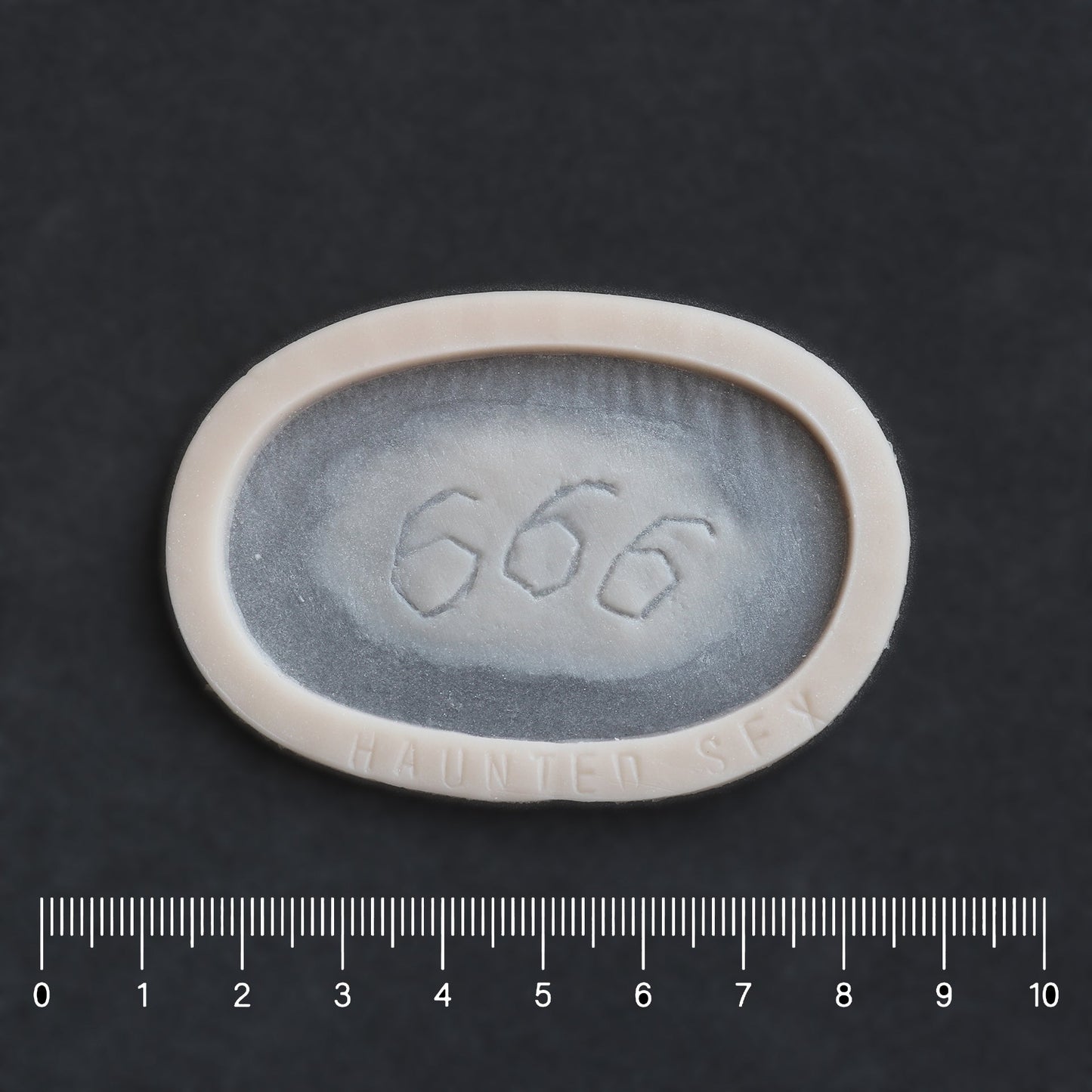 666 Carving prosthetic in vanilla shade on a black surface with a ruler