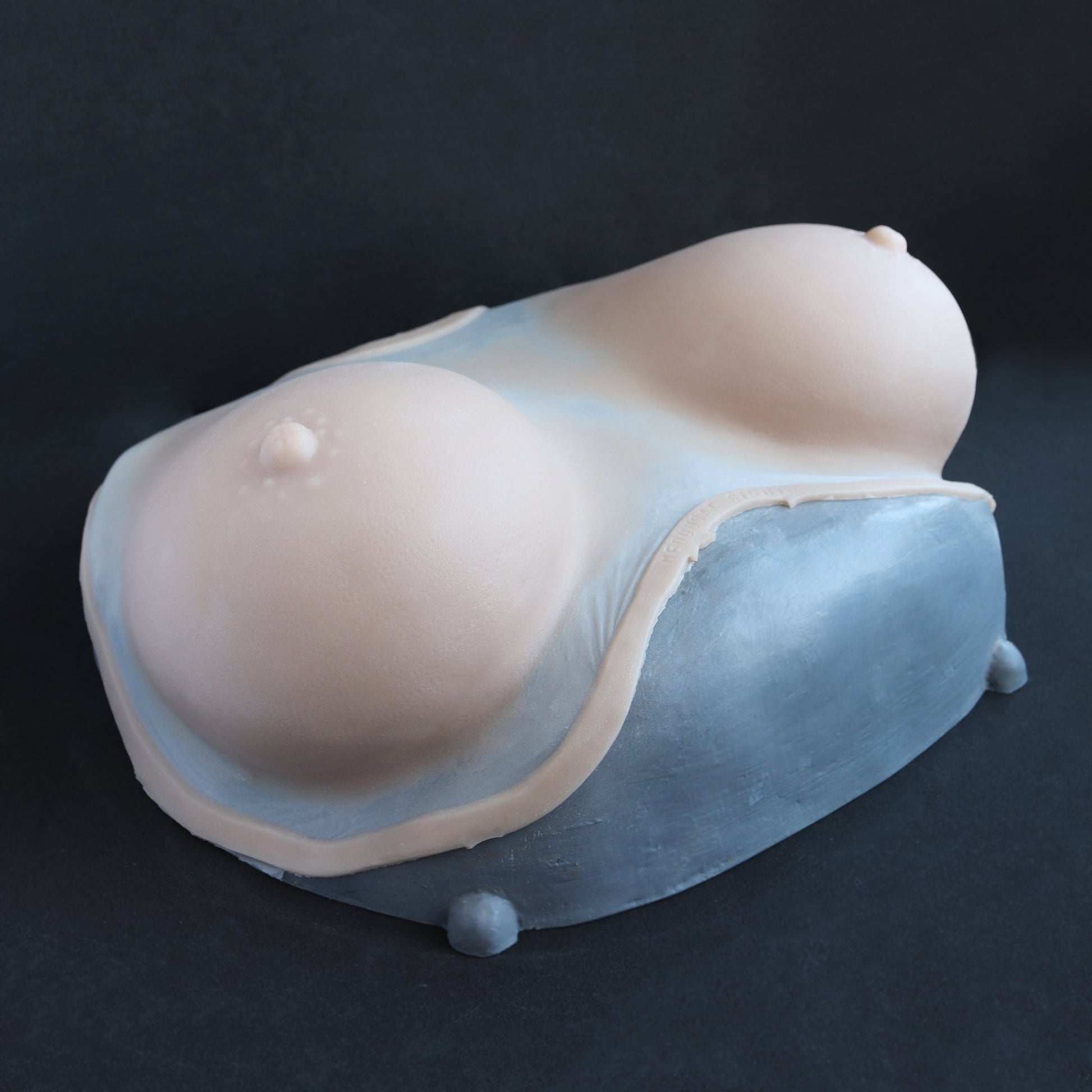 Breast Prosthetics - Silicone makeup prosthetic in vanilla shade on a black surface