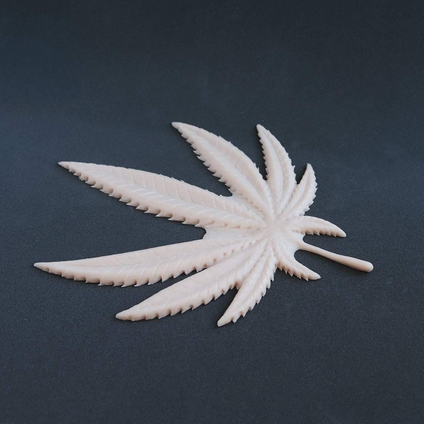 Cannabis Pasties / Nipple Patches (Pair) - Silicone makeup prosthetic in vanilla shade on a black surface at an angle