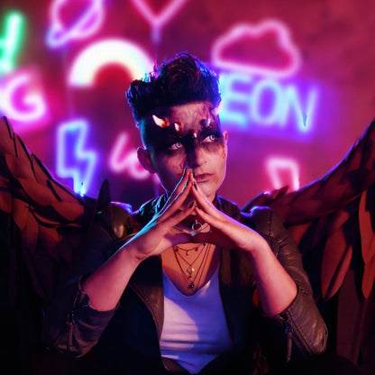 Woman with short hair wearing crooked horns, wings, and dark makeup