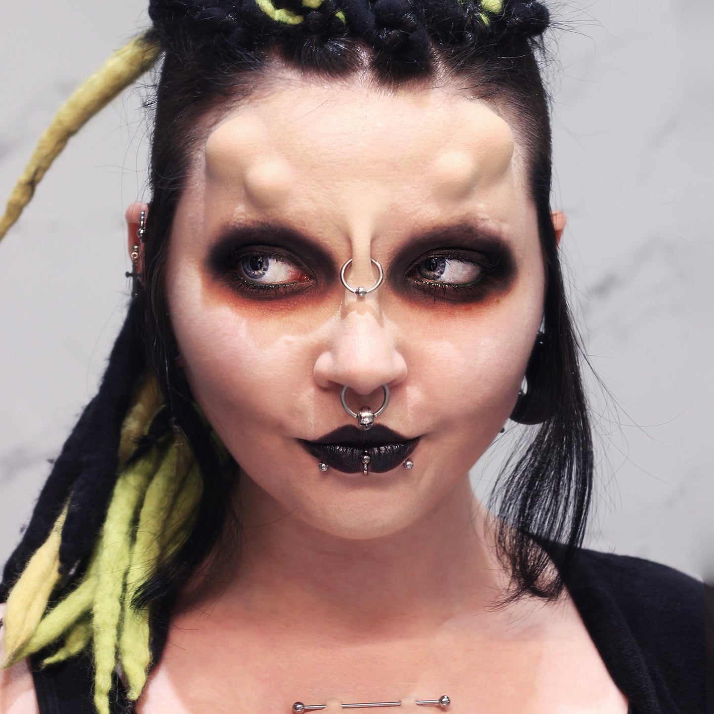 Woman with double subdermal horns and dark makeup