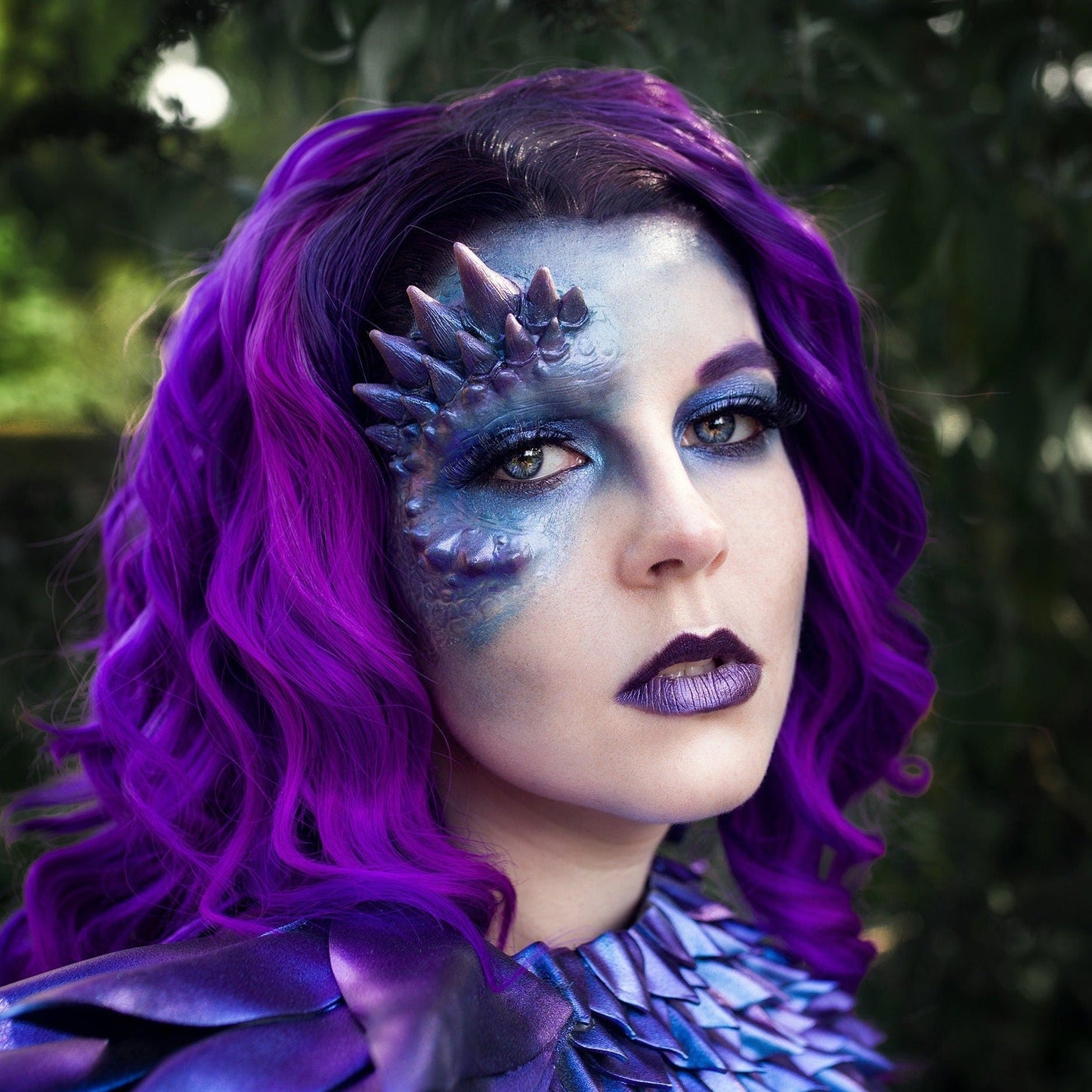 Woman with purple hair wearing a purple dragon half face prosthetic