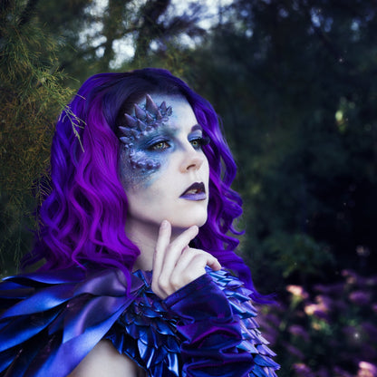 Woman with purple hair wearing a purple dragon half face prosthetic