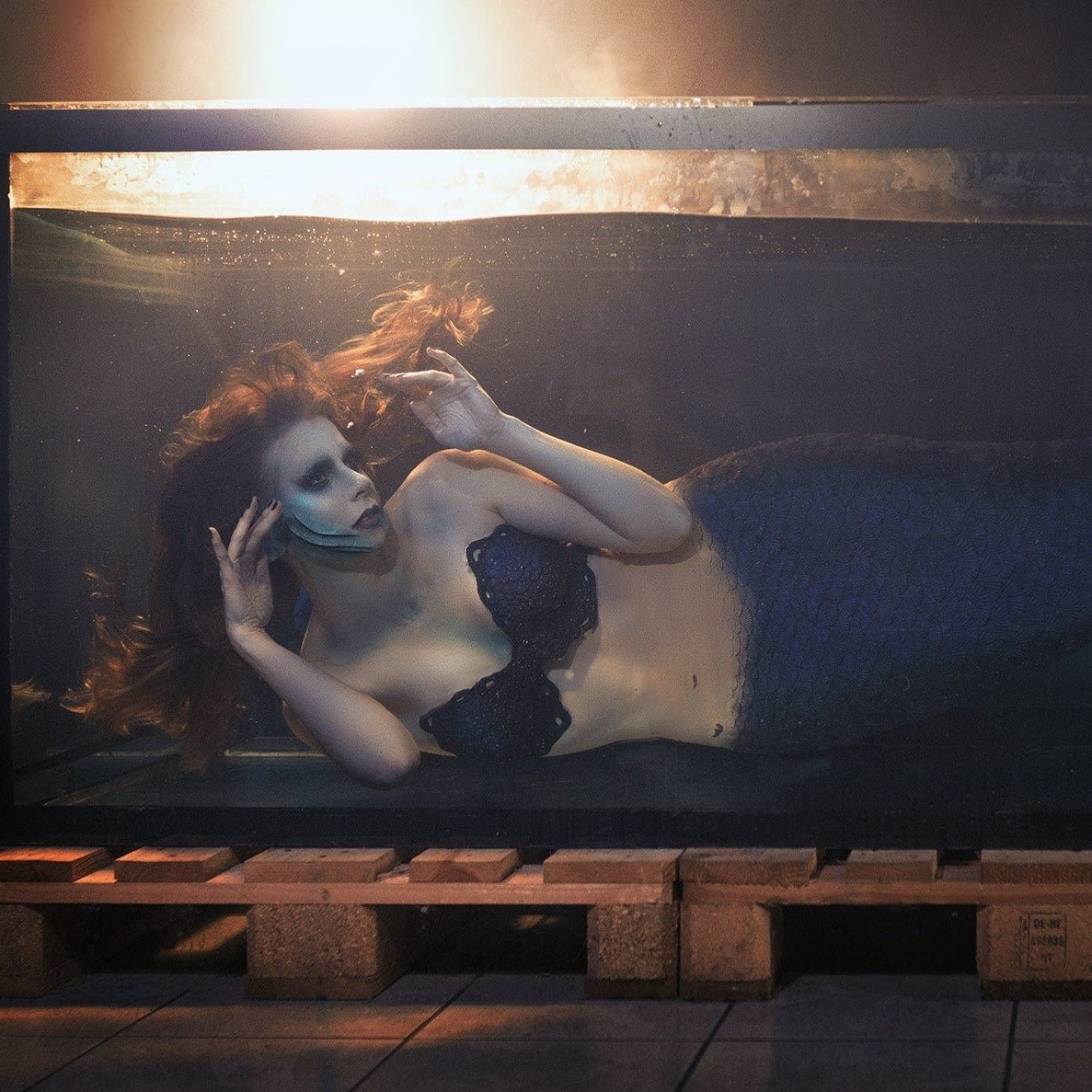 Mermaid, wearing mermaid gills, in a tank