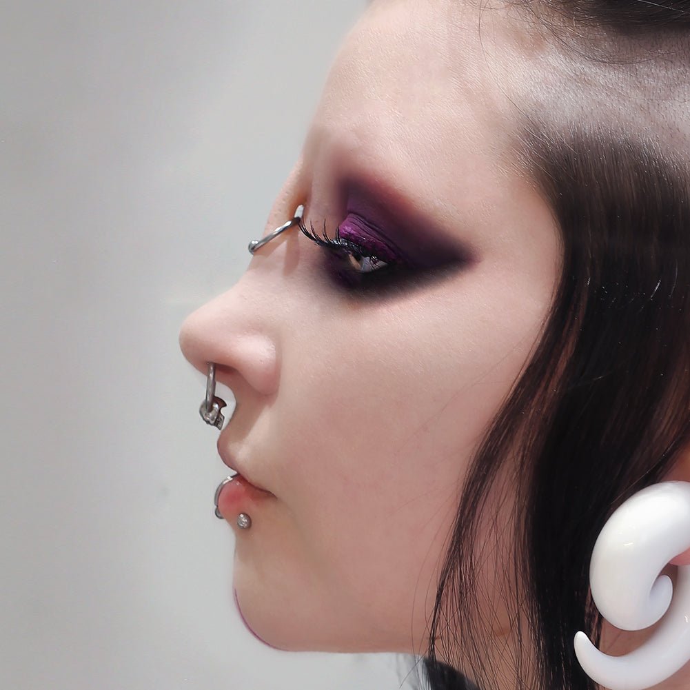 Woman with dark makeup wearing a nose bridge piercing prosthetic