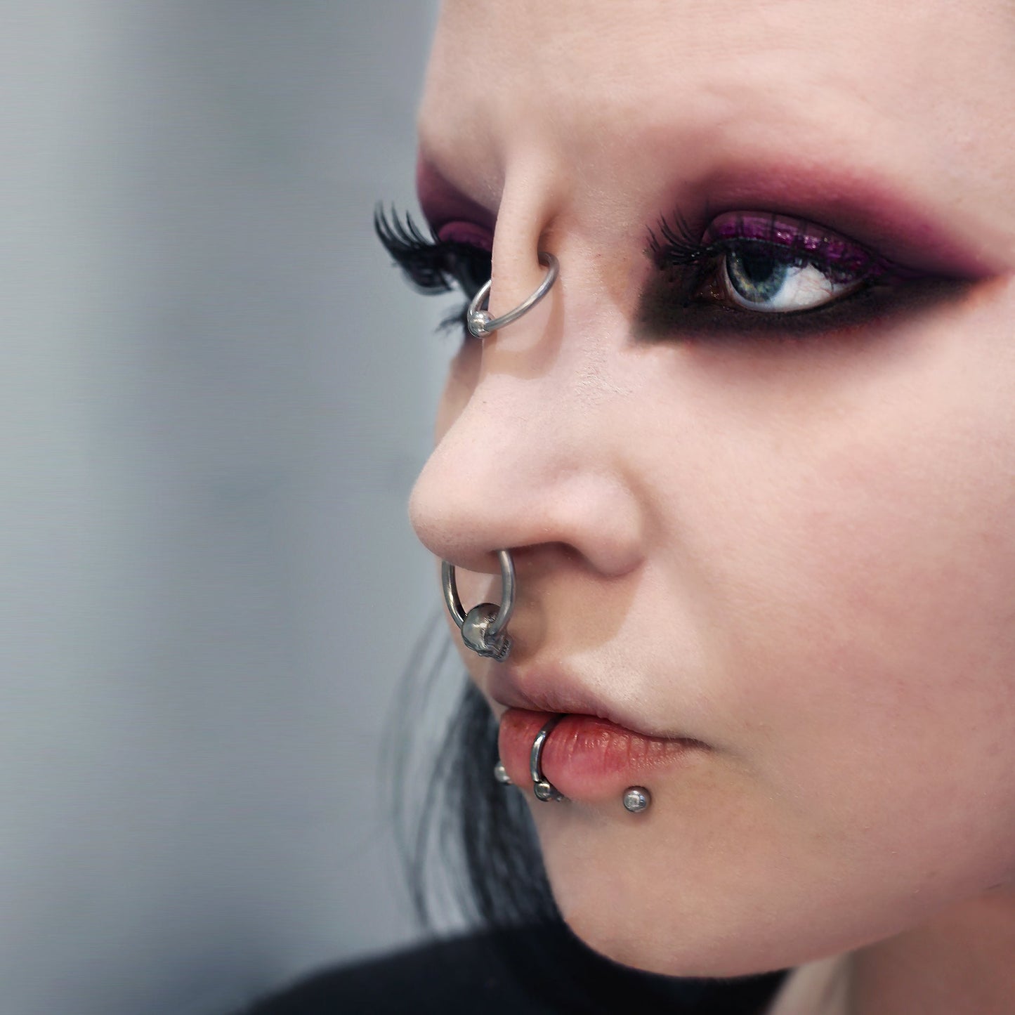 Woman with dark makeup wearing a nose bridge piercing prosthetic