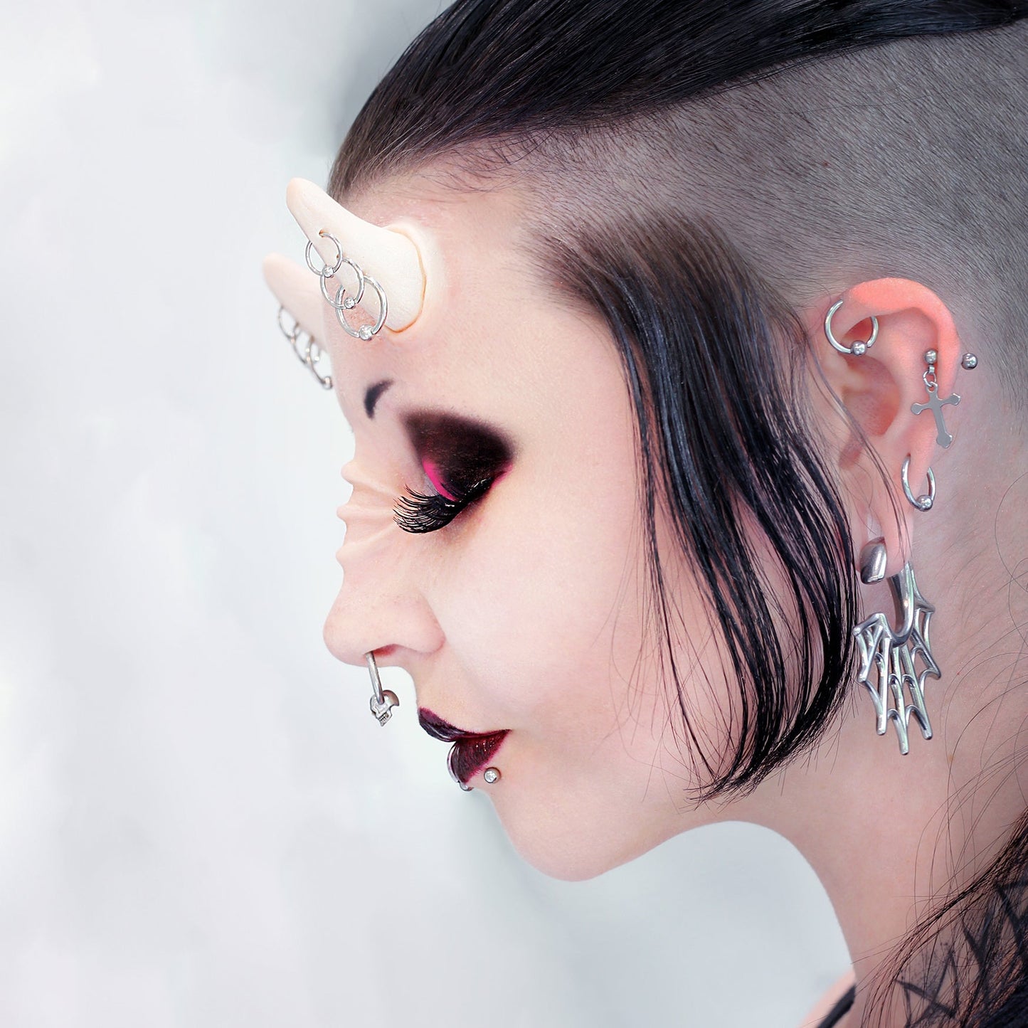 Woman with black hair wearing triple pierced horns and nose bridge ridges