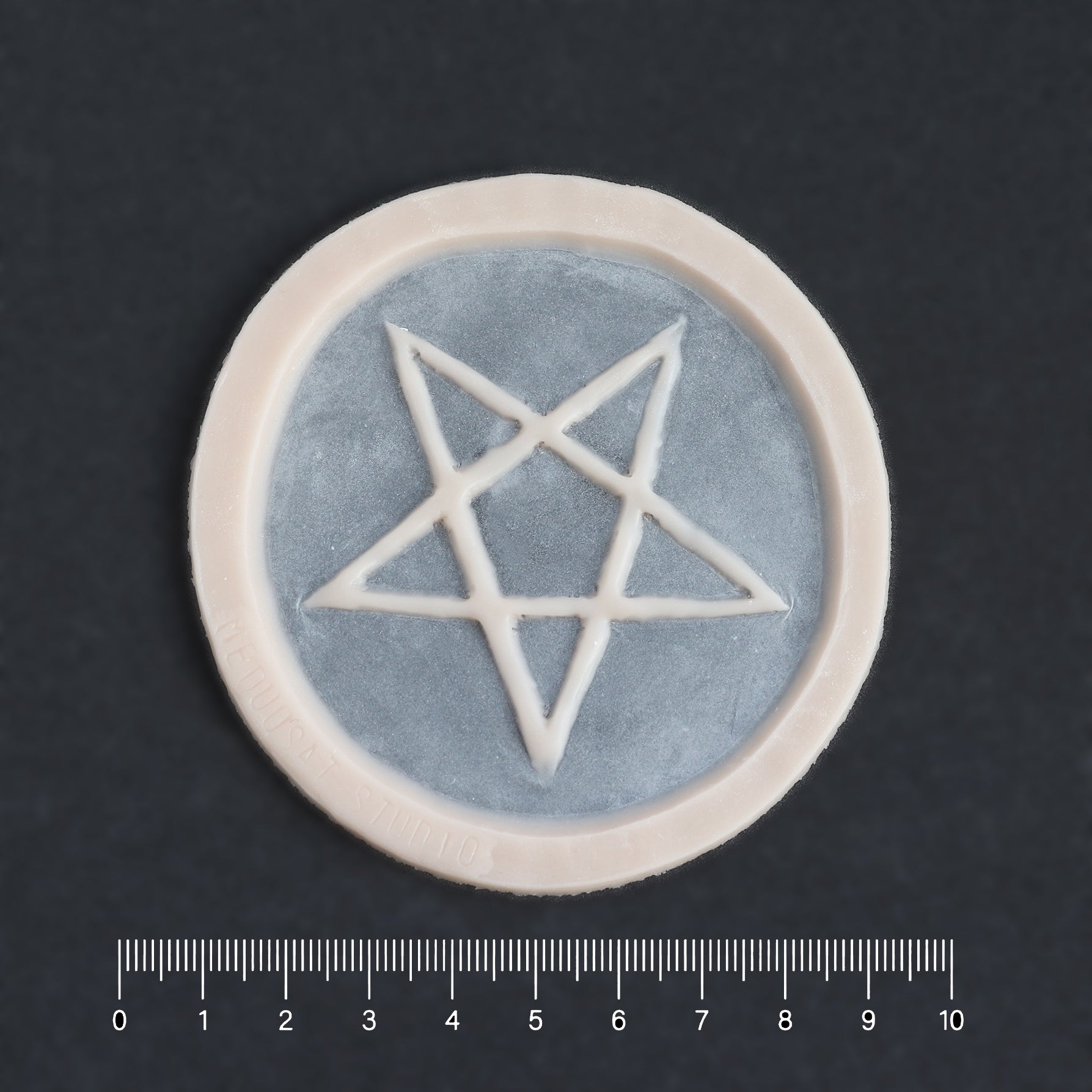 Pentagram Scarification - Silicone makeup prosthetic in vanilla shade on a black surface with a ruler