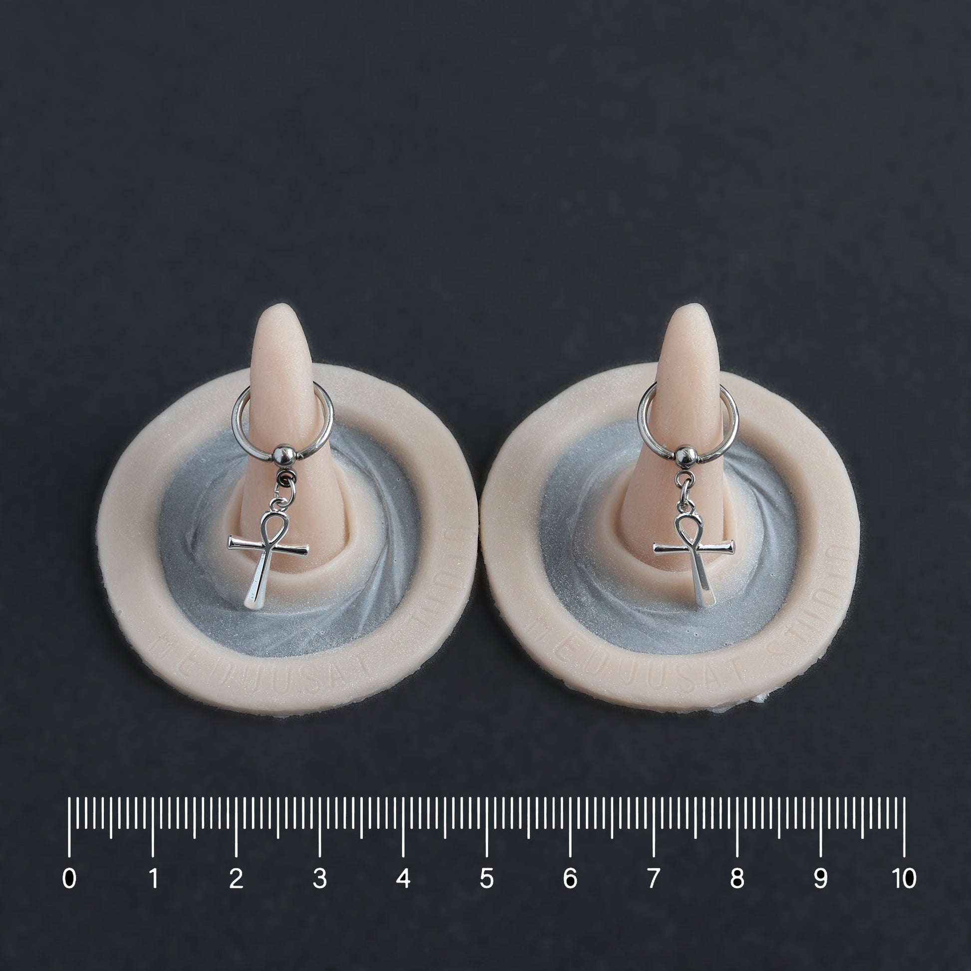 Pierced Horns (Pair) - Silicone makeup prosthetic in vanilla shade on a black surface with a ruler