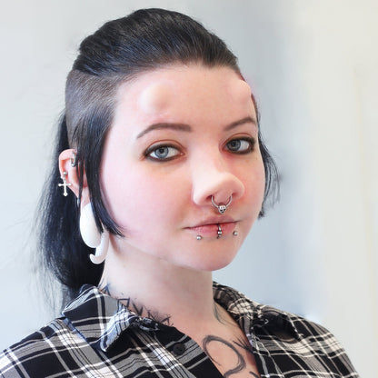 Woman with black hair wearing subdermal horns and a piglet nose prosthetic