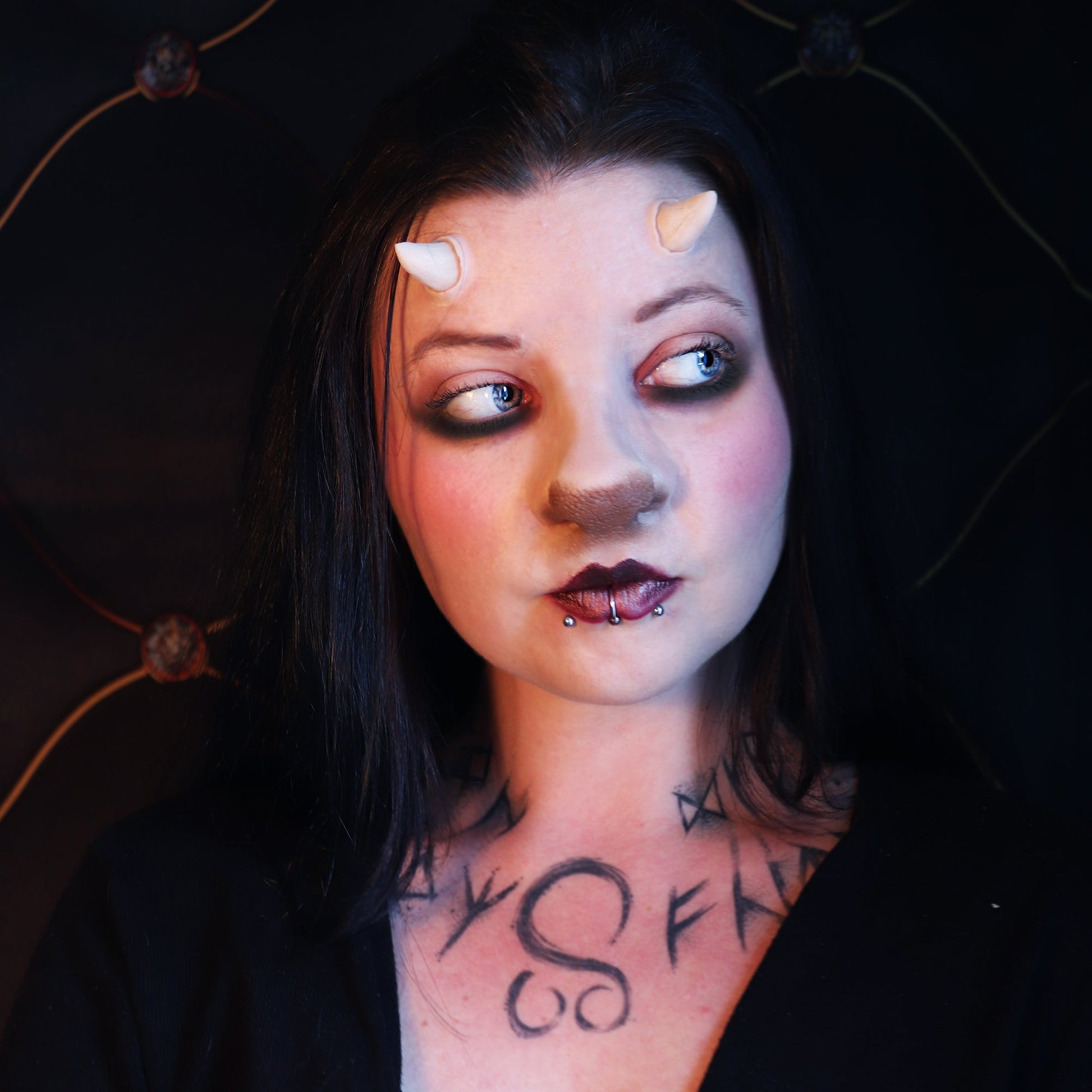 Woman with black hair wearing crooked horns and a satyr nose prosthetic