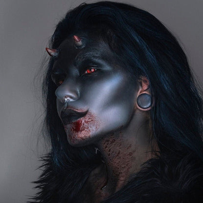 Woman in dark makeup wearing small devil horns