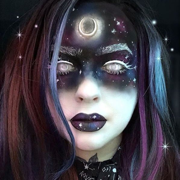 Woman with dark celestial makeup wearing a small moon prosthetic on her forehead