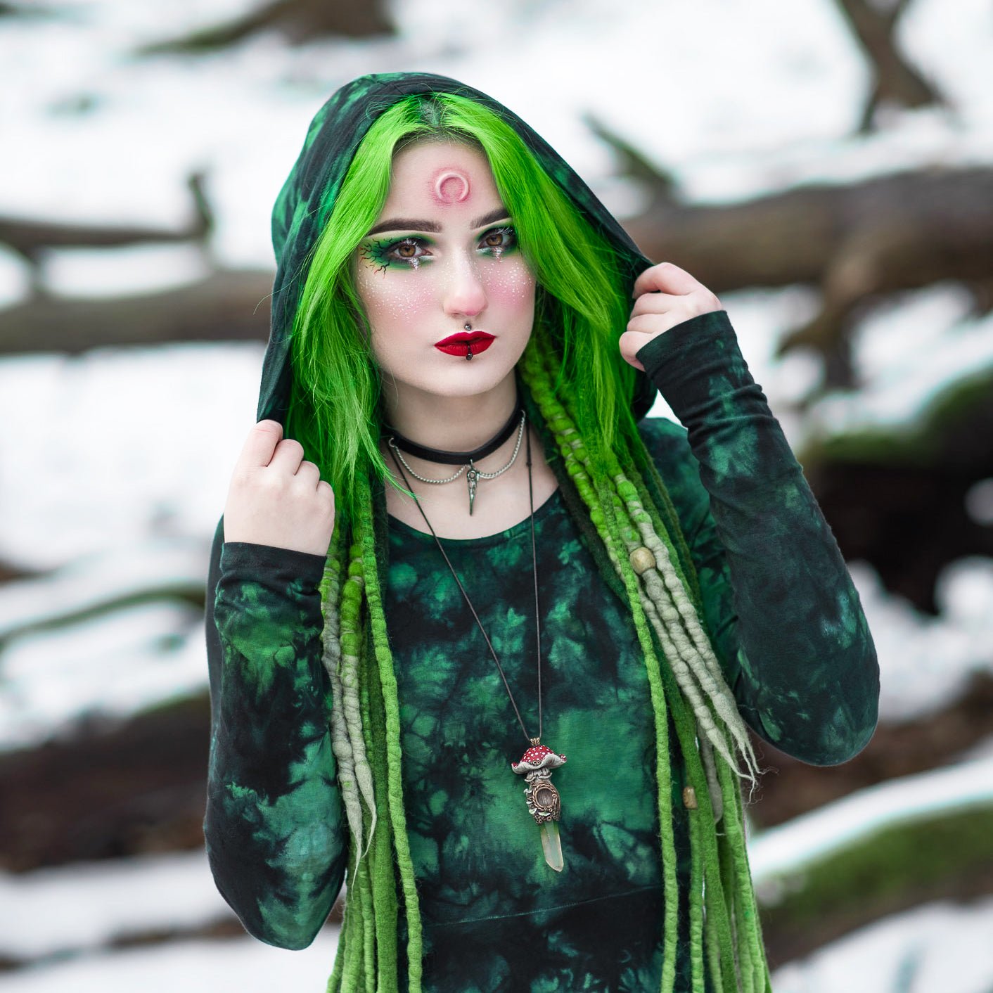 Woman with green hair wearing a small moon prosthetic on her forehead