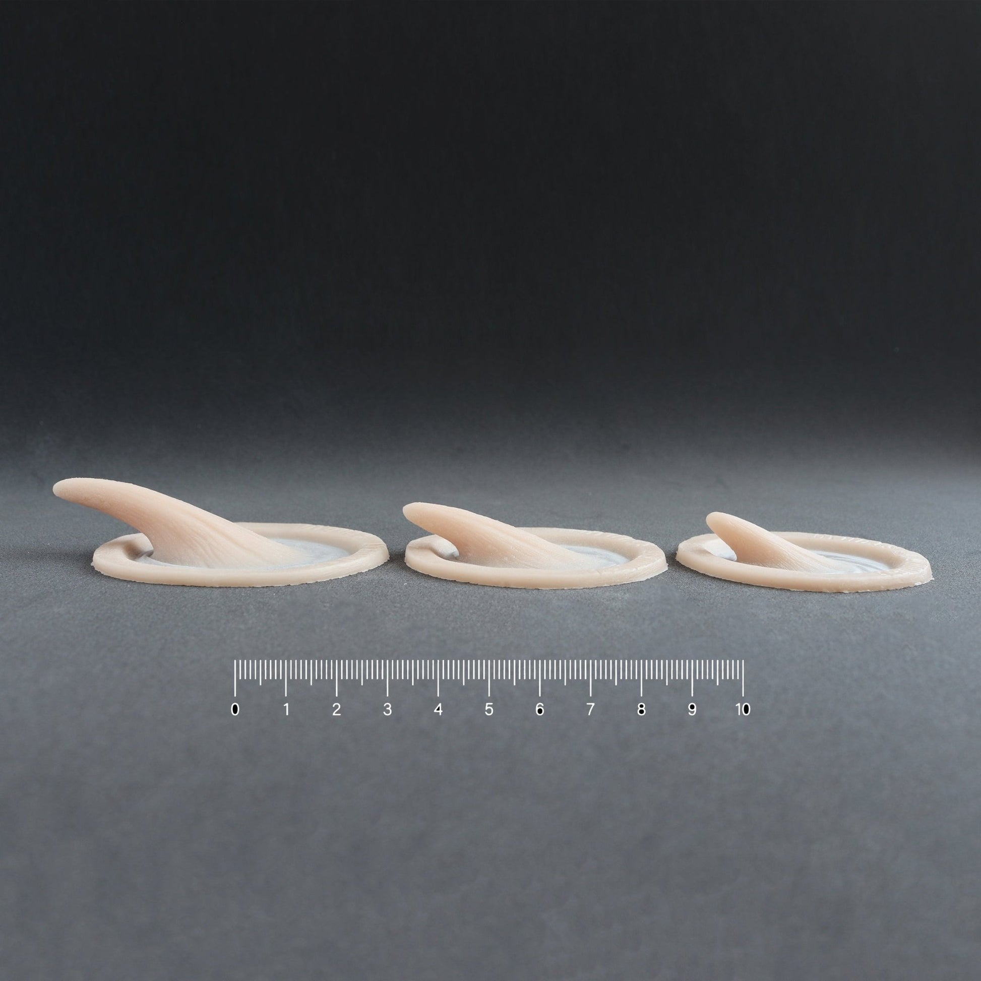 Small Vertical Horns (Pair) - Silicone makeup prosthetic in vanilla shade on a black surface with a ruler