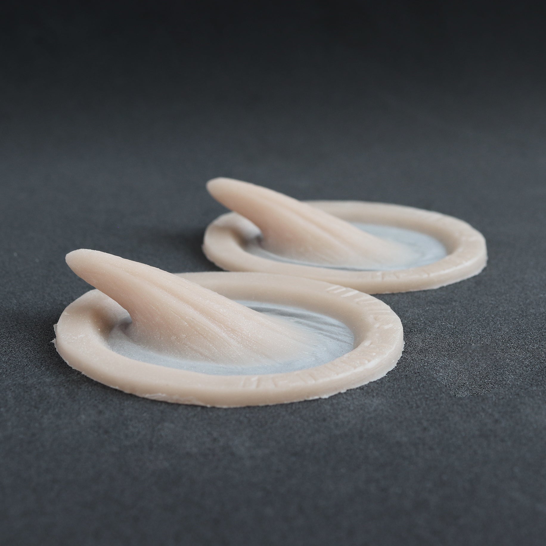 Small Vertical Horns (Pair) - Silicone makeup prosthetic in vanilla shade on a black surface