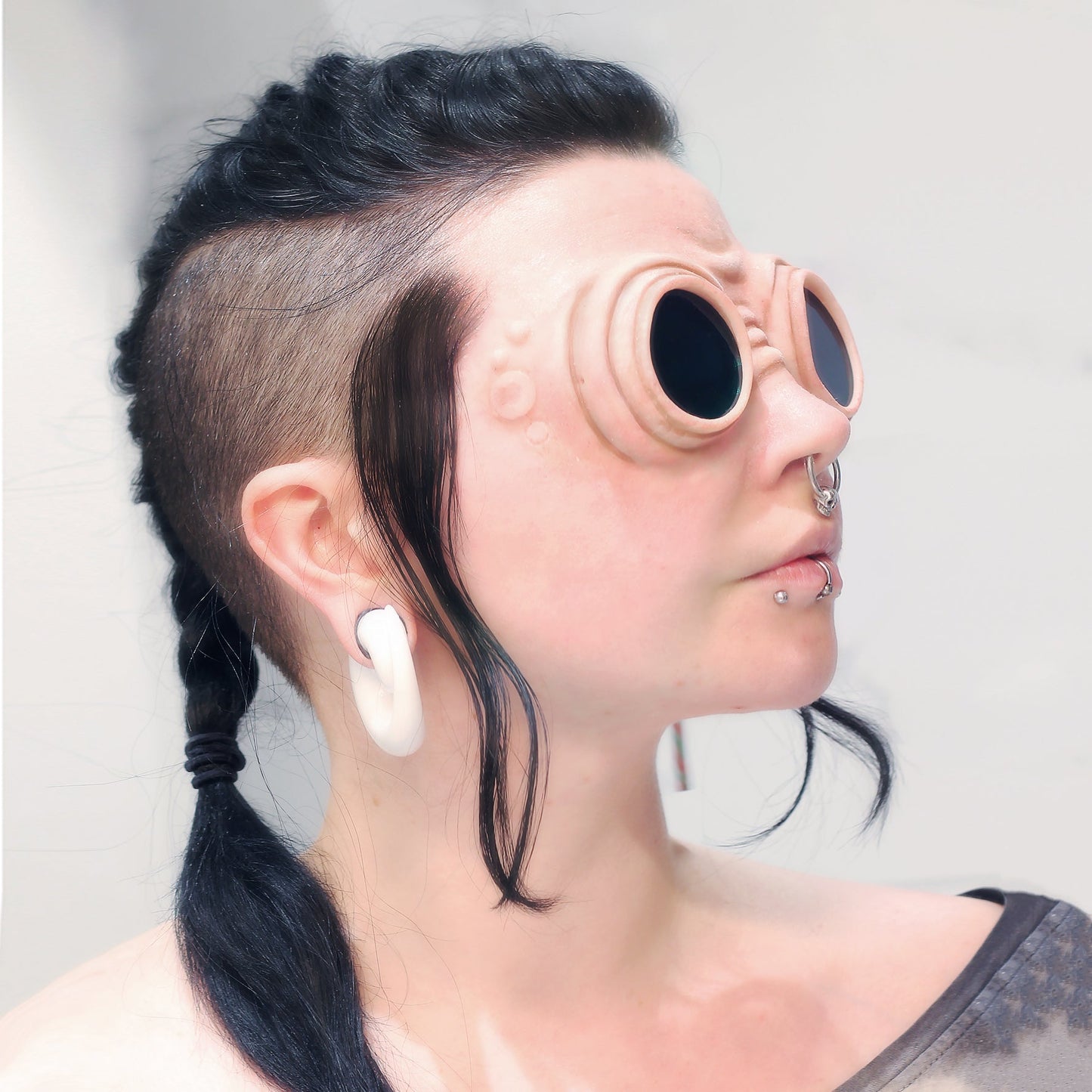 Woman with a black braid wearing goggle prosthetics