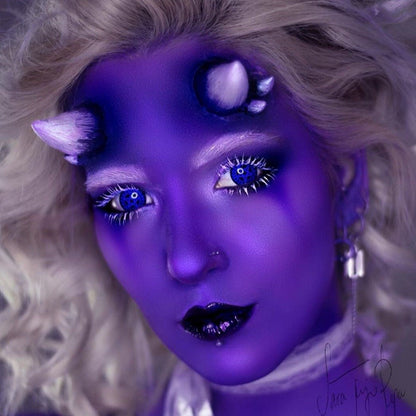 Woman with white hair in purple makeup wearing triple devil horns
