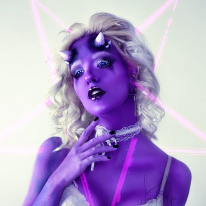 Woman with white hair in purple makeup wearing triple devil horns