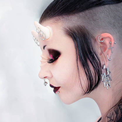 Woman with black hair wearing triple pierced horns and nose bridge ridges prosthetics