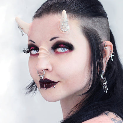 Woman with black hair wearing triple pierced horns and nose bridge ridges prosthetics
