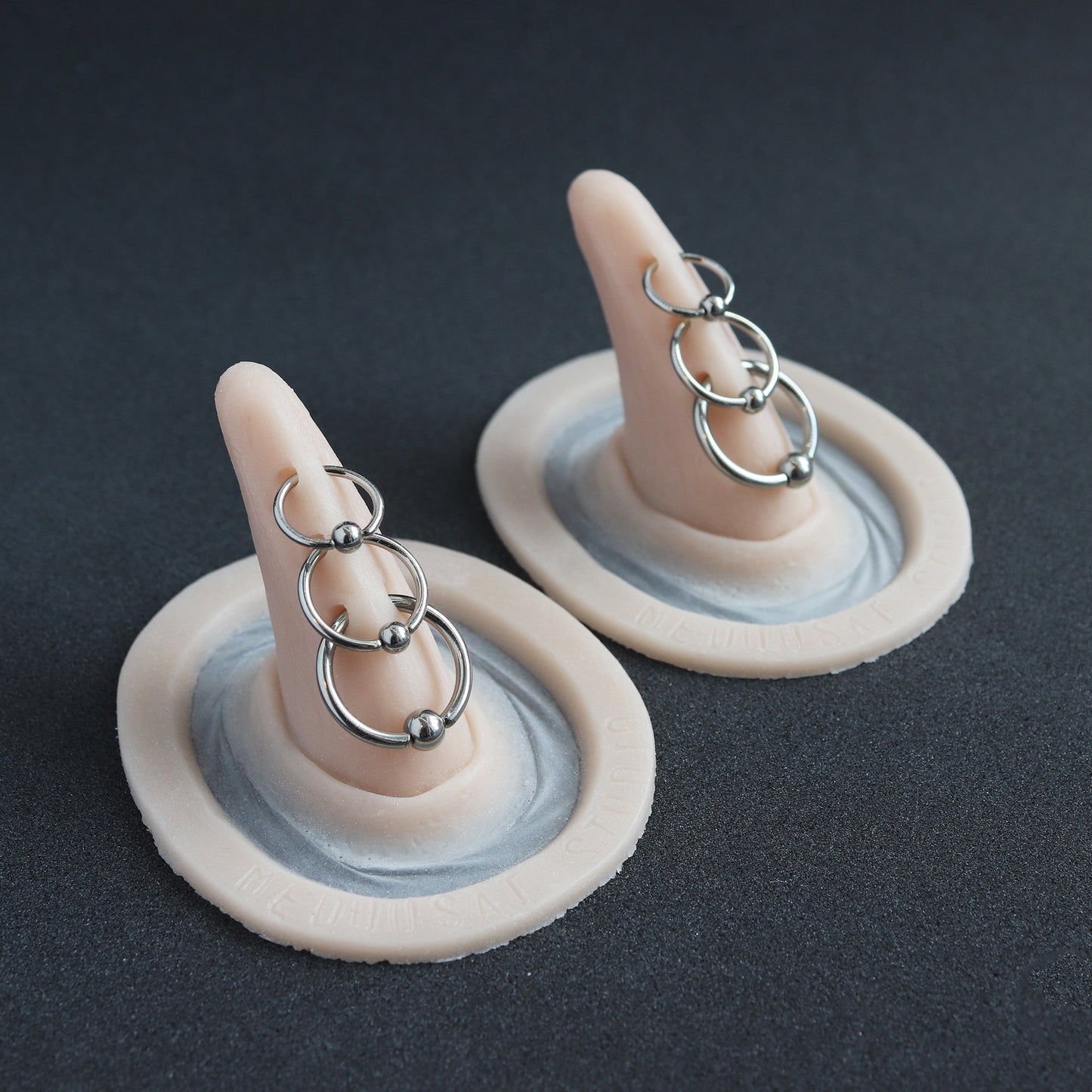 Triple Pierced Horns (Pair) - Silicone makeup prosthetic in vanilla shade on a black surface
