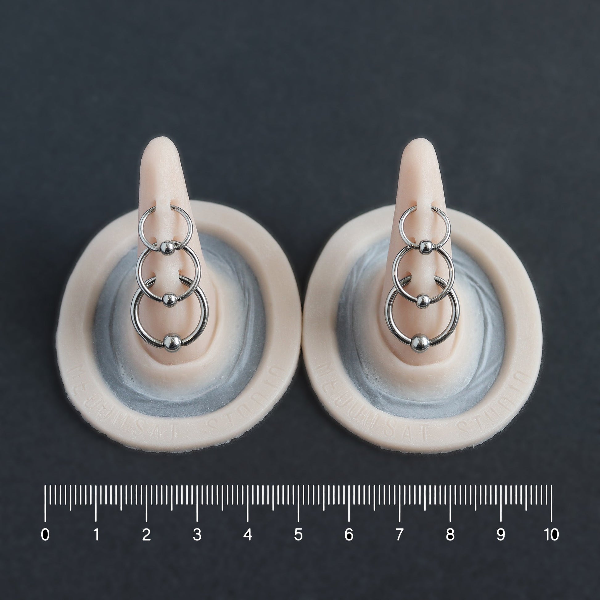 Triple Pierced Horns (Pair) - Silicone makeup prosthetic in vanilla shade on a black surface with a ruler