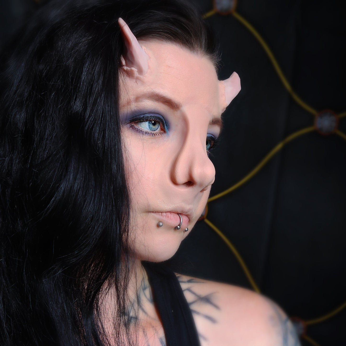 Woman with black hair wearing torn horns and a whelk nose prosthetic